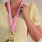 Person wearing a yellow shirt with a pink lanyard and keychain against a plain background