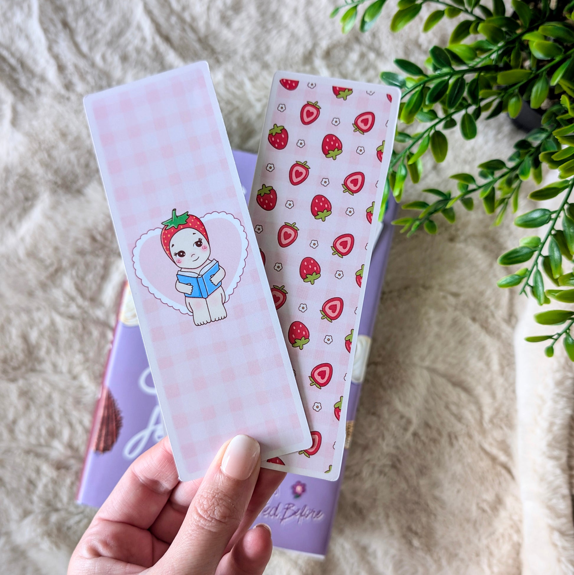Hand holding a set of stationery items with strawberry design on a textured surface.