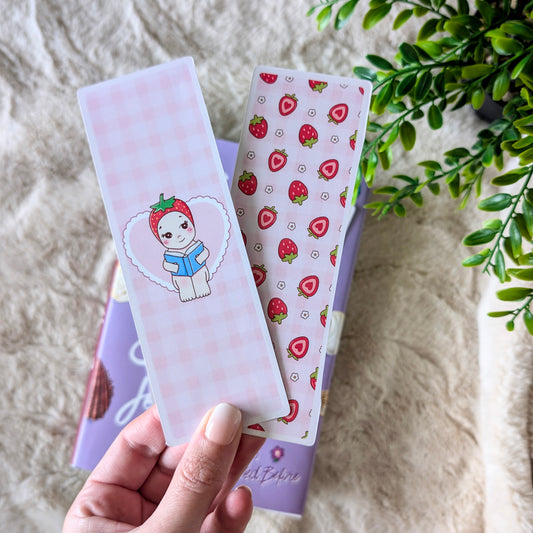 Hand holding a set of stationery items with strawberry design on a textured surface.