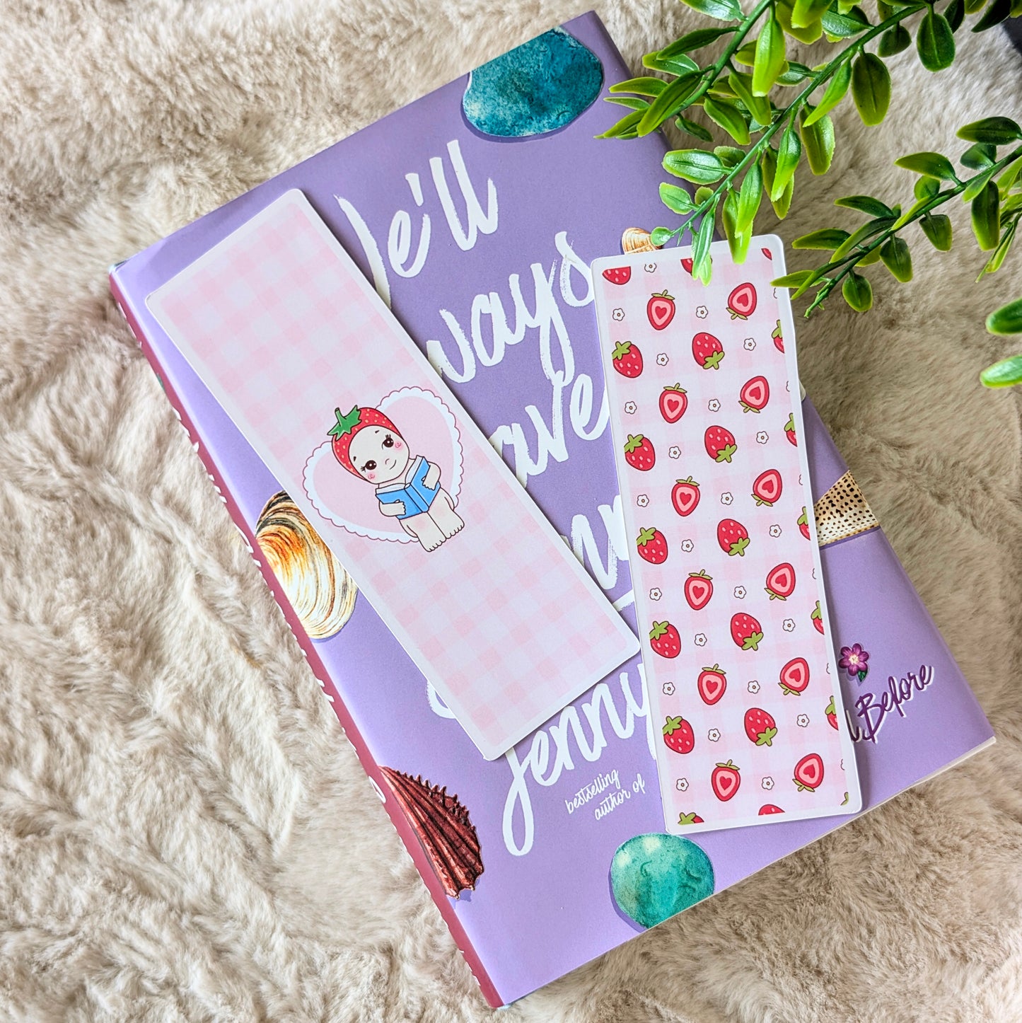 Purple notebook with a white bookmark featuring a snowman and strawberry pattern on a fluffy surface.