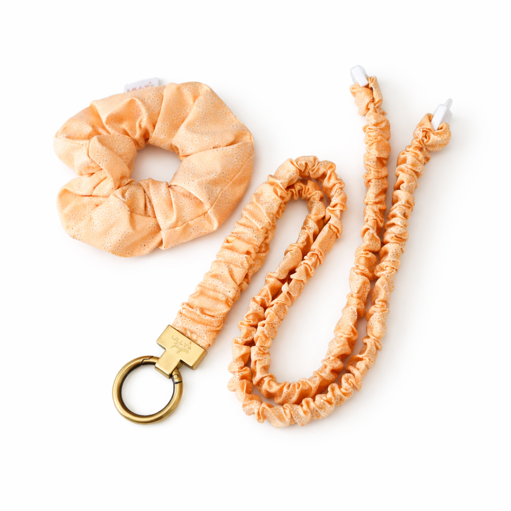 Set of peach scrunchie, lanyard, and keychain on a white background