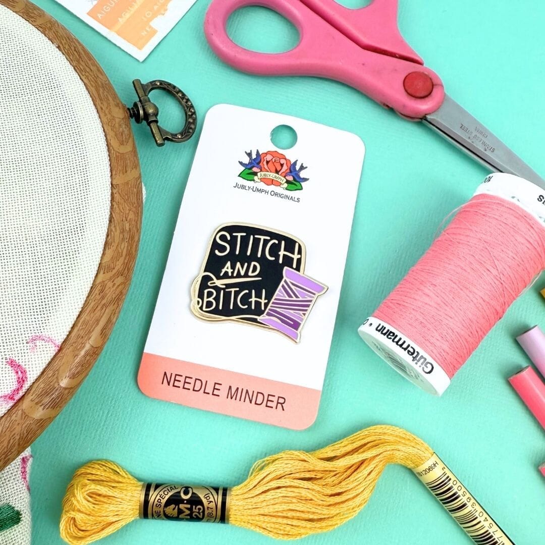 Stitch and Bitch needle minder with embroidery supplies on a teal background